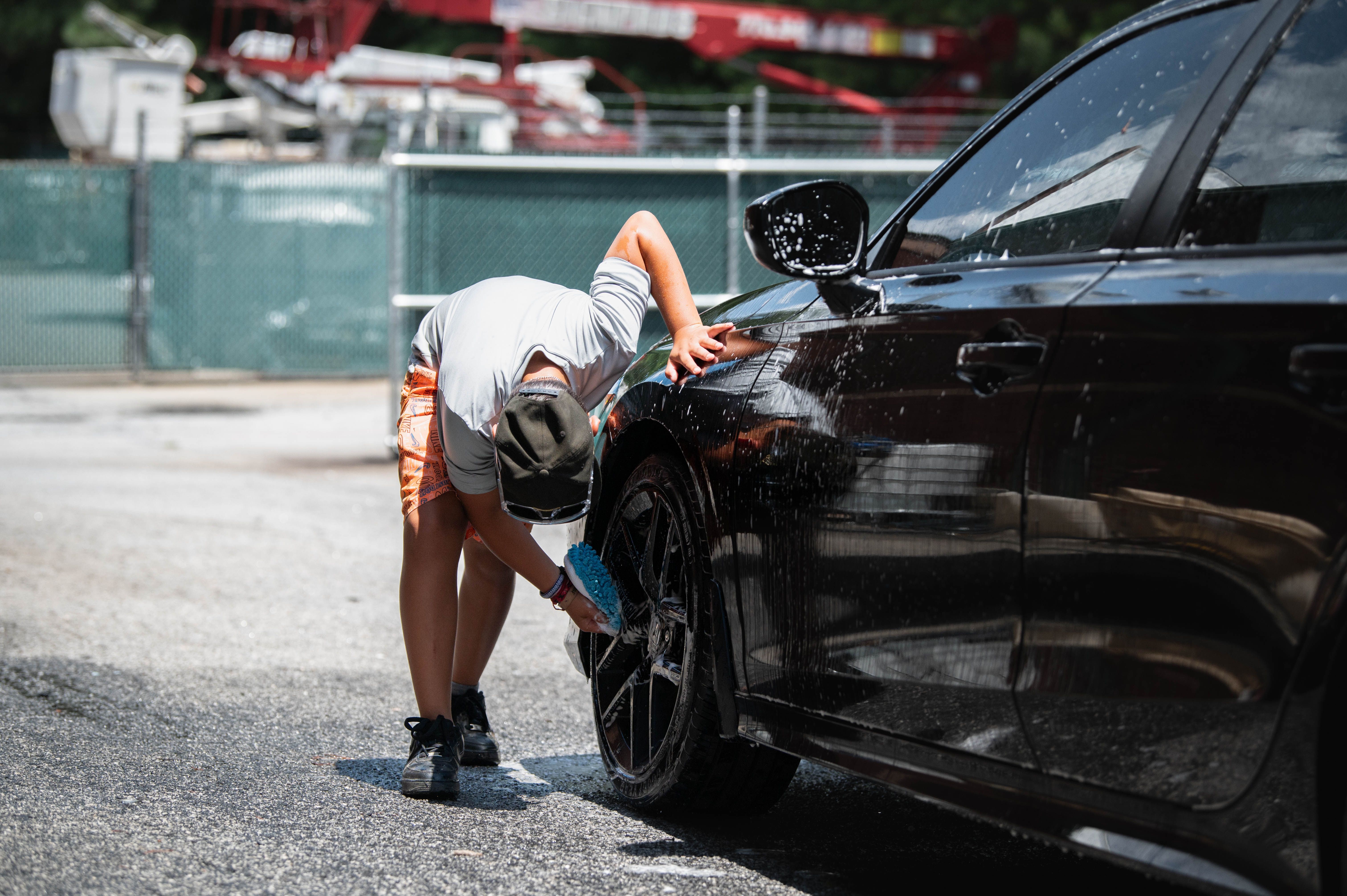 Profissional aplicando proteção cerâmica na pintura de um automóvel preto